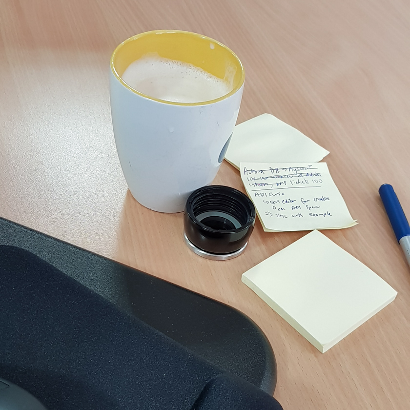A coffee cup on a desk next to some post its.